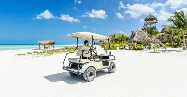 A man driving a golf cart on the beach.