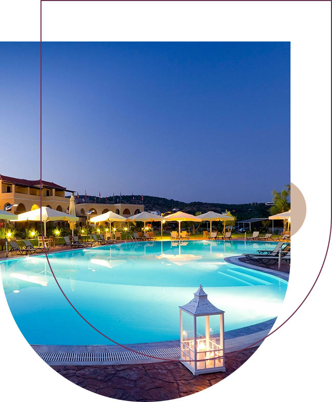 A pool with lights and umbrellas in the background.