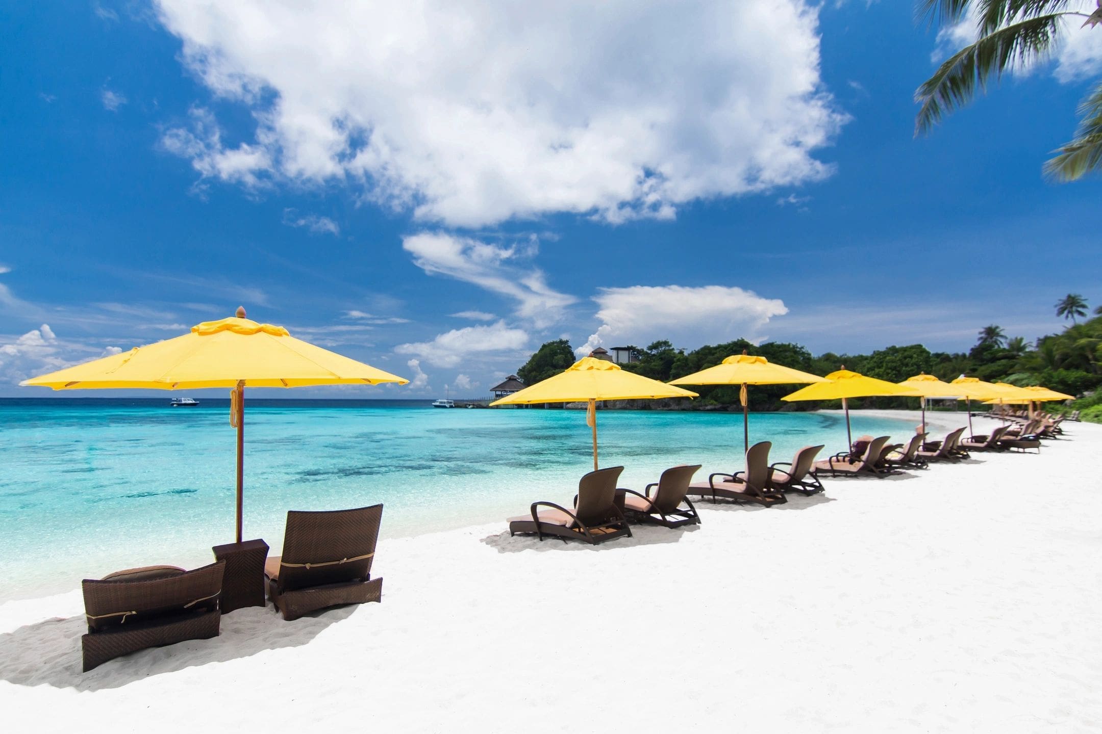 A beach with several chairs and umbrellas on the sand.