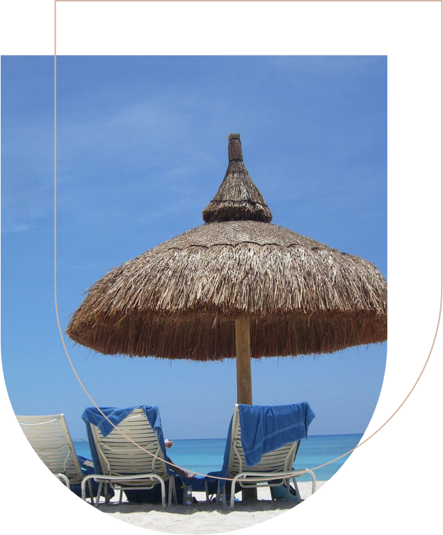 A straw umbrella and two lawn chairs on the beach.